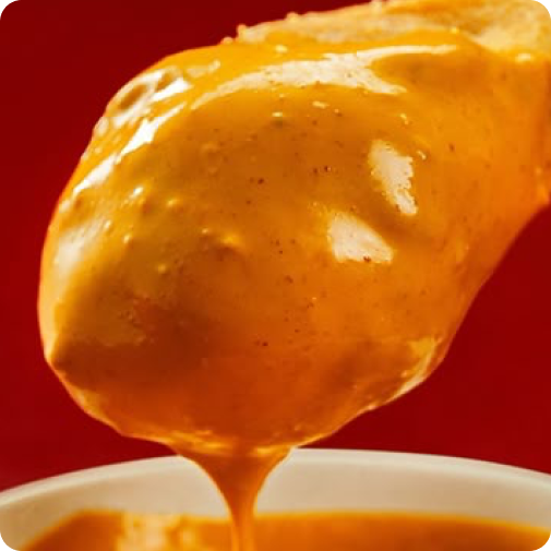 Close-up of a spoonful of orange sauce against a red background